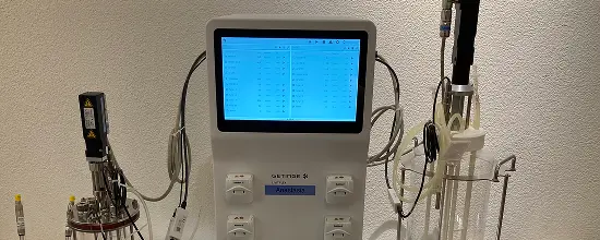 Benchtop controller connected to a glass bioreactor with tubing and sensors, set up for the hands-on session